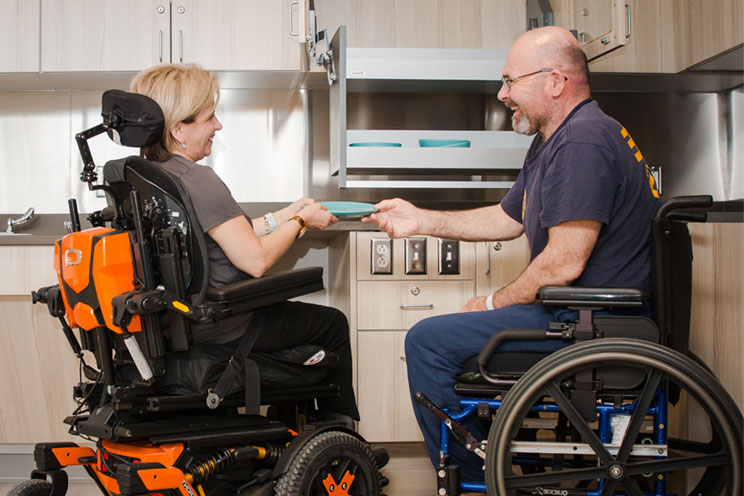 Two rehab patients putting dishes away in the kitchen at the Independent Living Simulation Suites