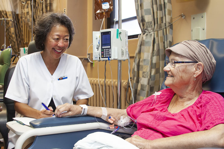 A nurse administering cancer treatment to female patient at the QEII