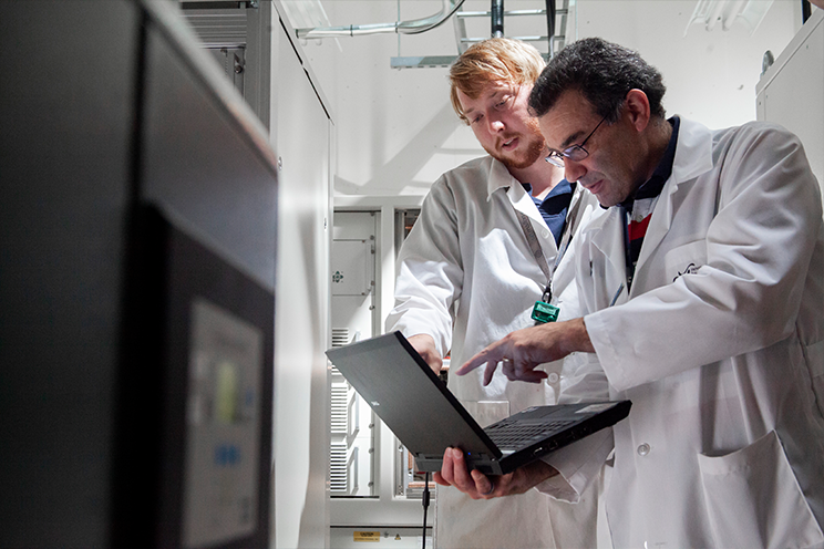 Two research technicians analyzing data on a laptop