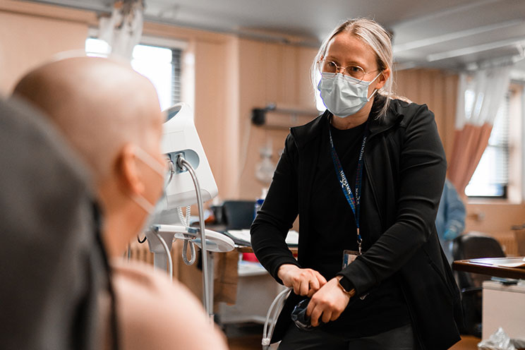 A QEII registered nurse speaks with a patient during their treatment. 