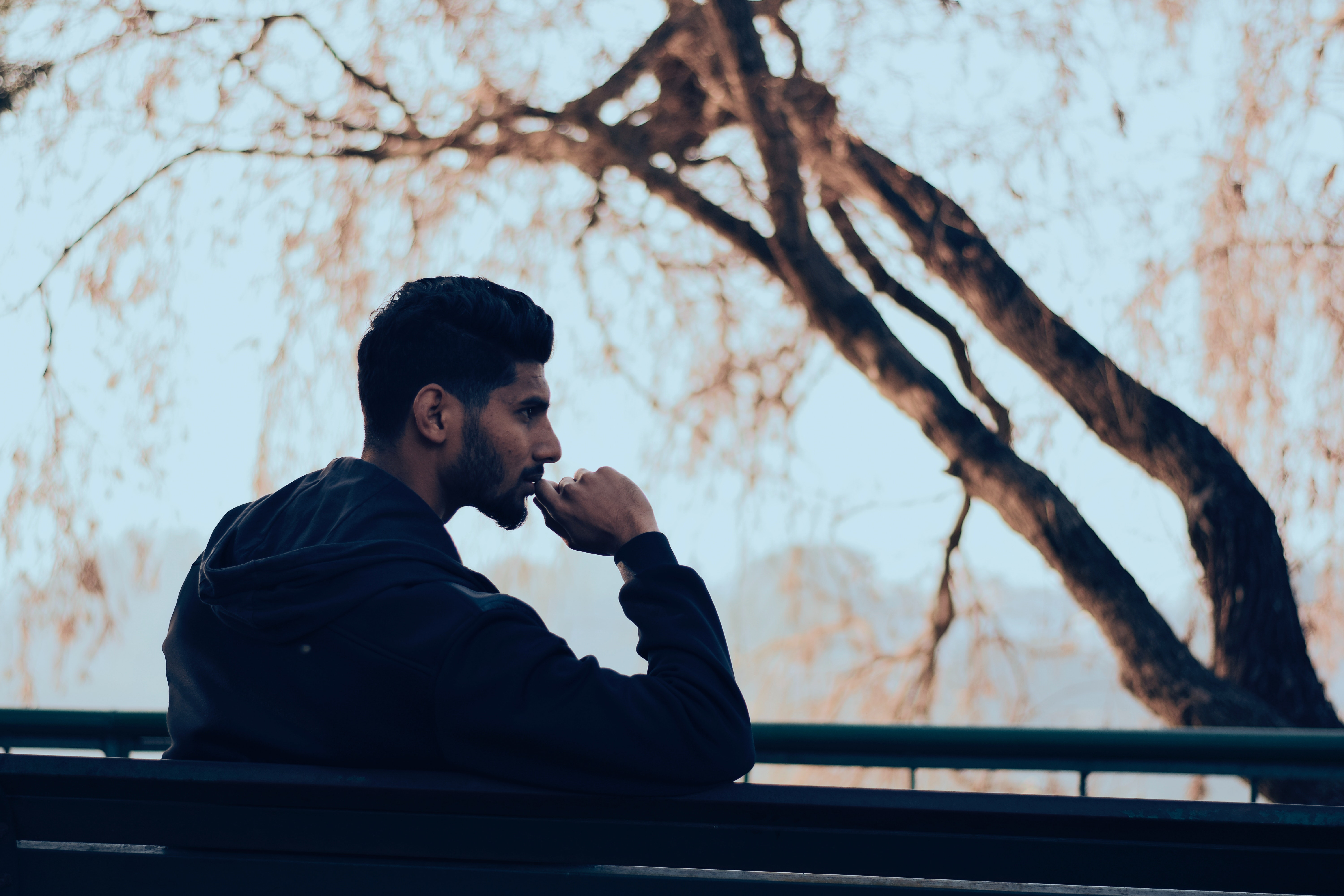 A man sits on a bench, in a contemplative state 