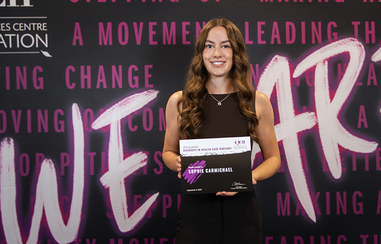 Student Sophie Carmichael smiles as she holds her Diversity in Health Care Bursary.