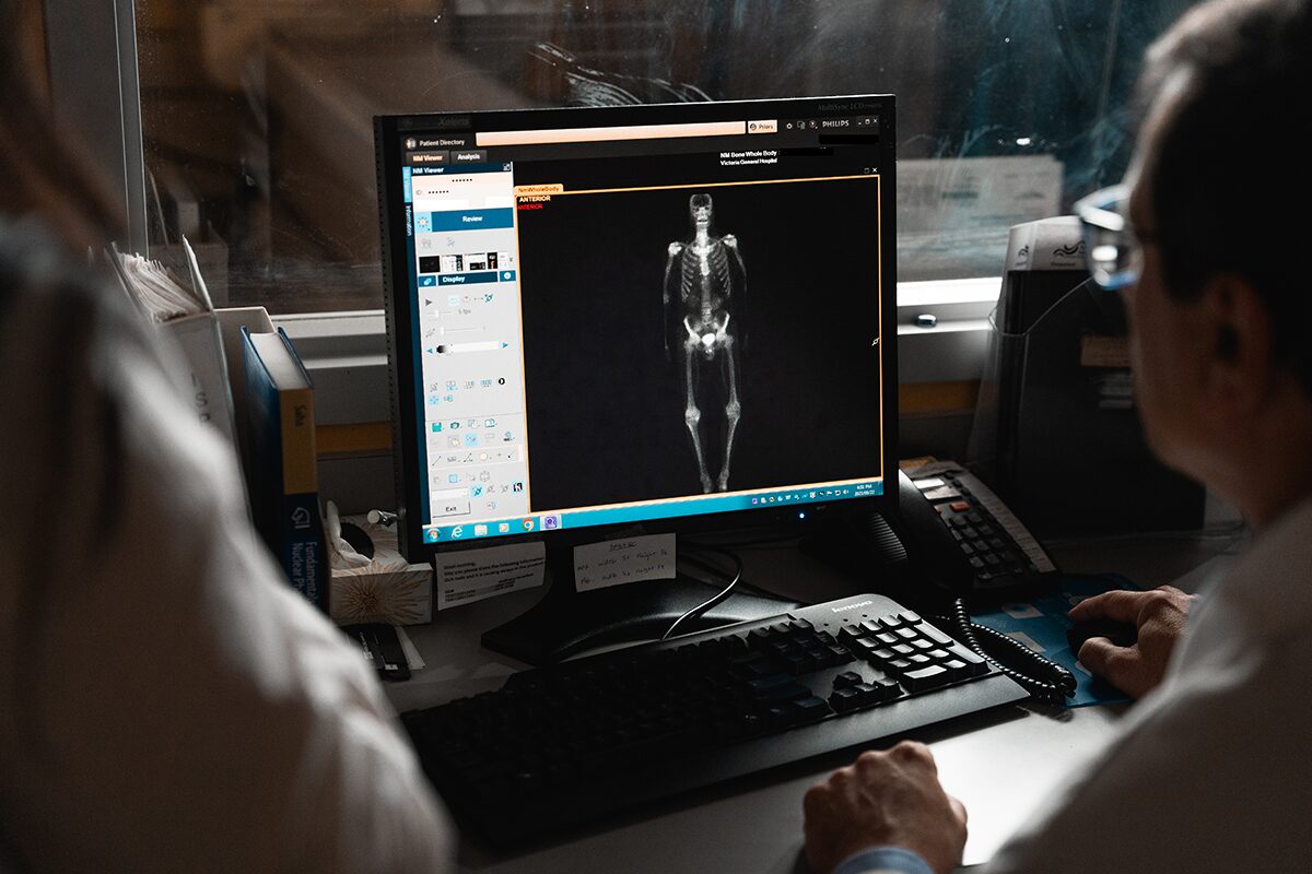 Two people in a hospital are looking at a computer screen with a full-body scan showing on the screen.
