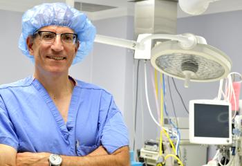 Dr. Hirsch stands in his blue scrubs in front of medical equipment 