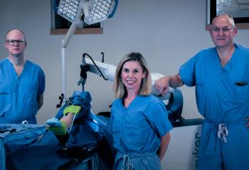 Dr. Glen Richardson, Janie Wilson, PhD and Dr. Michael Dunbar stand with the orthopaedic surgical robot.