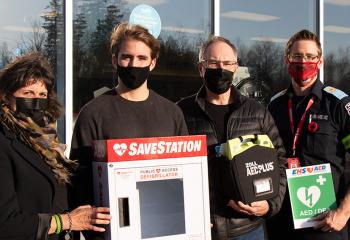 Debbie Boyd, Bronson Beaton, Stephen Boyd and Mike Janczyszyn stand outside of the Oxford Irving, holding a donated automated external defibrillator.