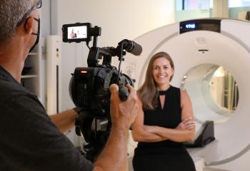 A video camera captures footage of Sharon Needham, who sits in from of a PET-CT scanner at the QEII