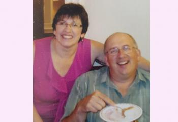 A man and woman sitting, smiling at the camera. 