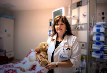 Dr. Sarah McMullin holds a donor-funded teddy bear provided through Teddy Bears with Heart