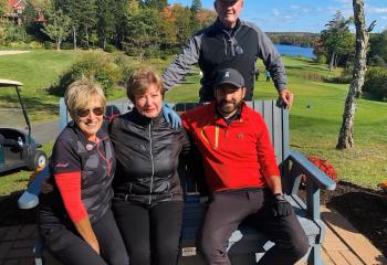 Individuals sitting on bench at a sunny golf course