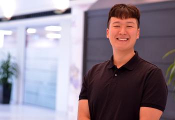 Sean Wang stands smiling, wearing a black t-shirt