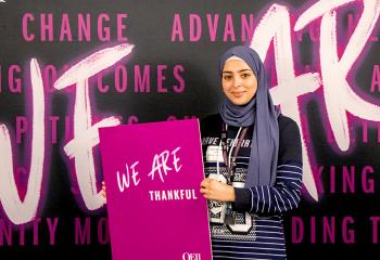 Ayah holding a sign in front of a celebration backdrop