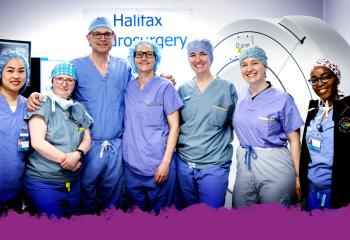 A group of doctors in an operating room, wearing scrubs and smiling at the camera. 