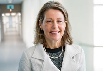 Dr, Sharon Mulvagh wearing a white blazer in a medical hallway