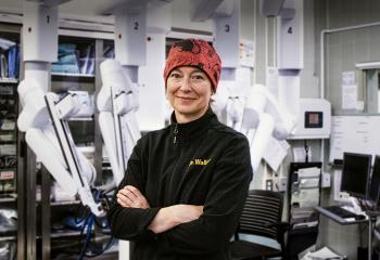 Dr. Allison Wallace poses with the daVinci Xi surgical robot in the background.