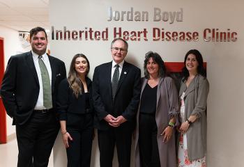The Boyd family stands under the sign at the QEII's Jordan Boyd Inherited Heart Disease Clinic.