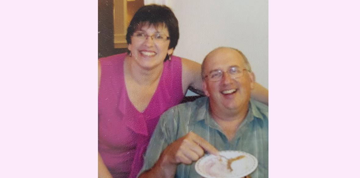 A man and woman sitting, smiling at the camera. 