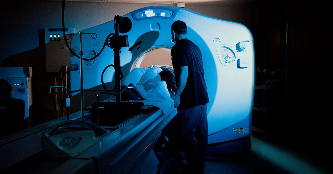 Radiation therapist comforts a patient being scanned by the QEII's CT simulator machine, which resembles a CT scanner