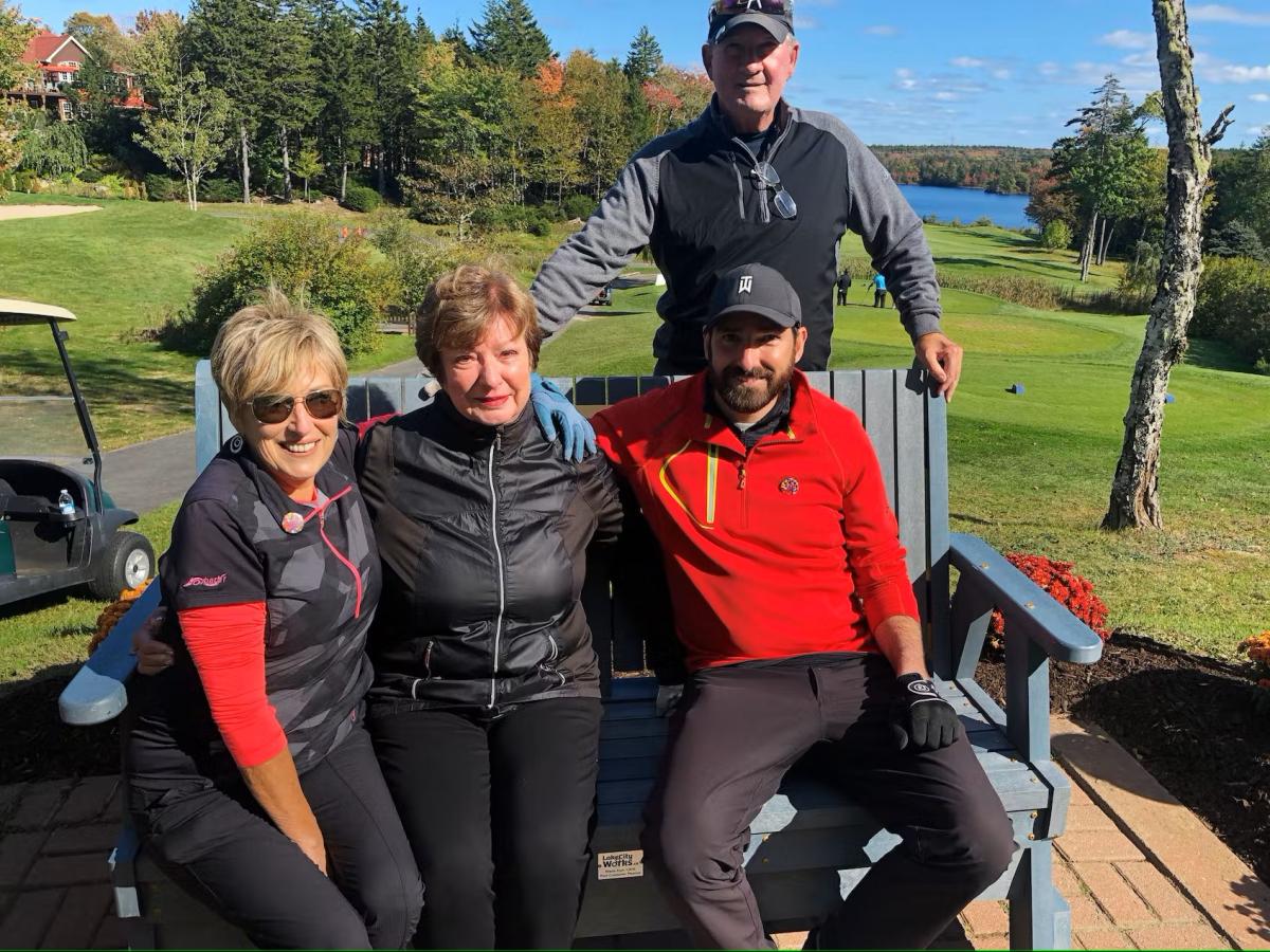 Individuals sitting on bench at a sunny golf course