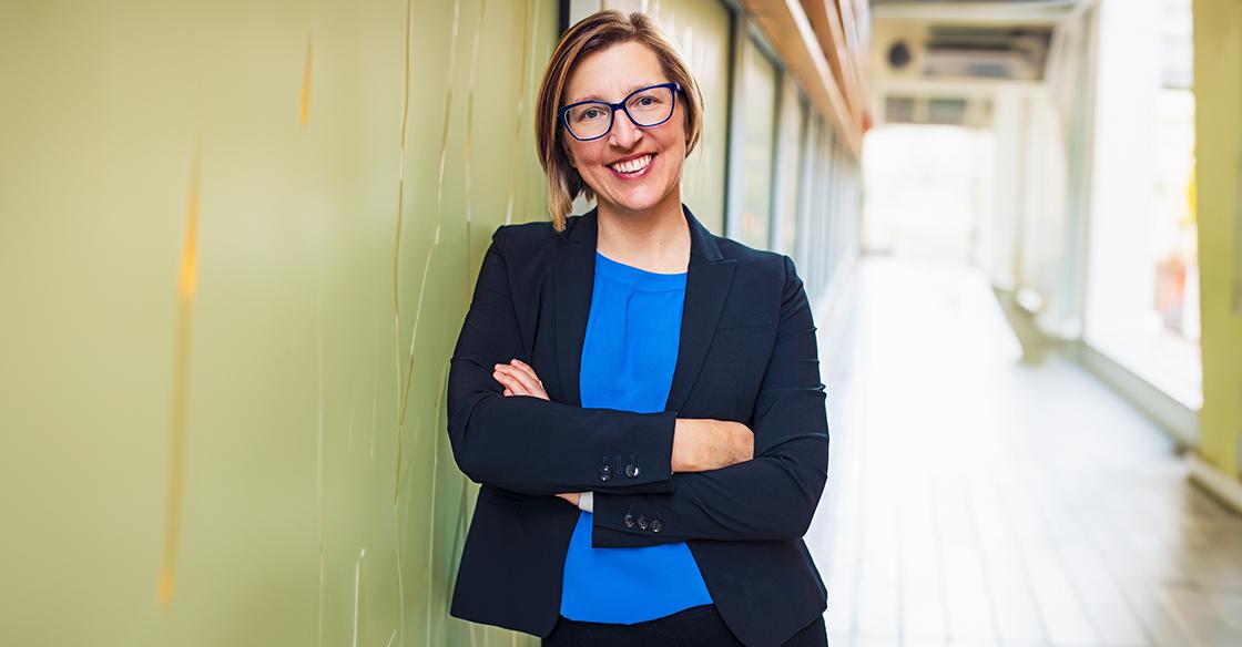 Dr. Robin Urquhart stands smiling in a hallway