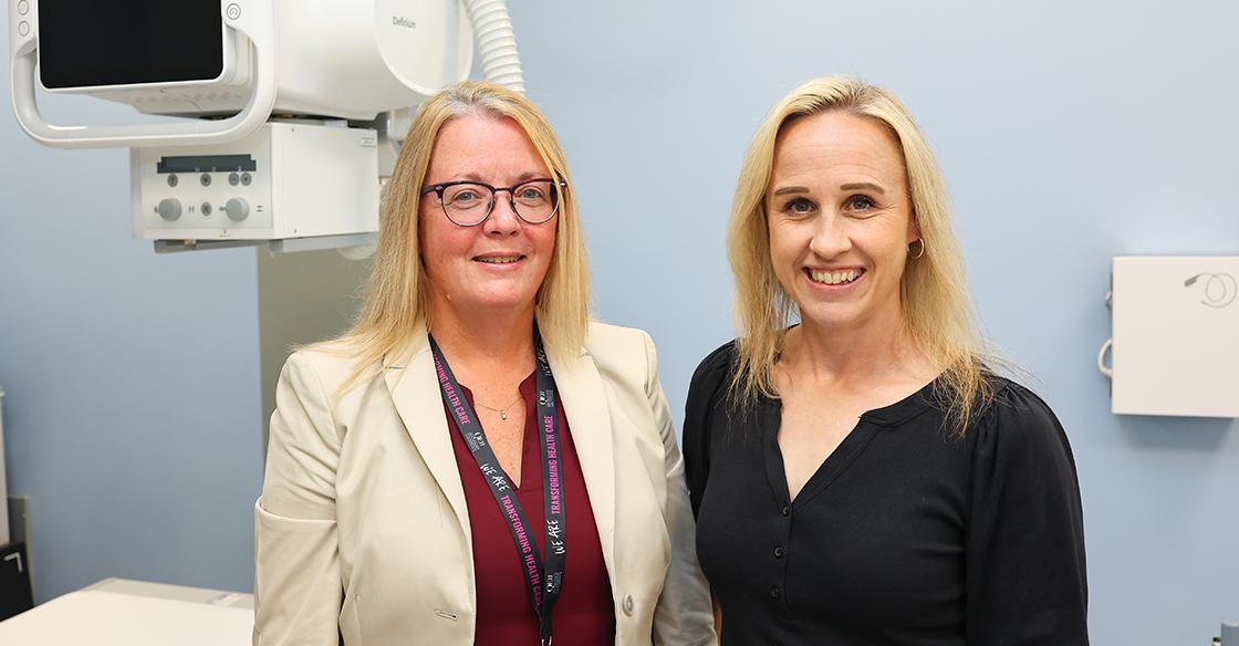 Two women stand in front of the newly acquired Precision 180 Fluoroscopy Unit at the QEII’s Rehab Centre.