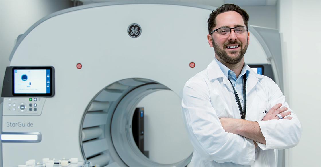 Doctor stands in front of nuclear medicine scanning technology