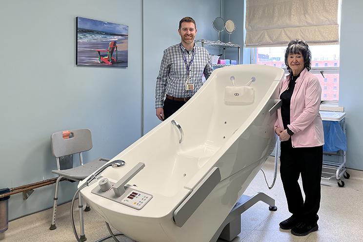 Two palliative care staff stand by the accessible whirlpool tub.