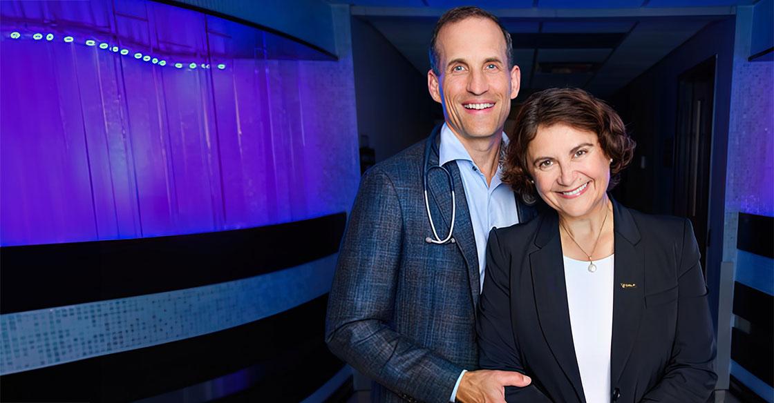 Drs. Rutlege and Ilie pictured in front of purple wall in the QEII Cancer Centre