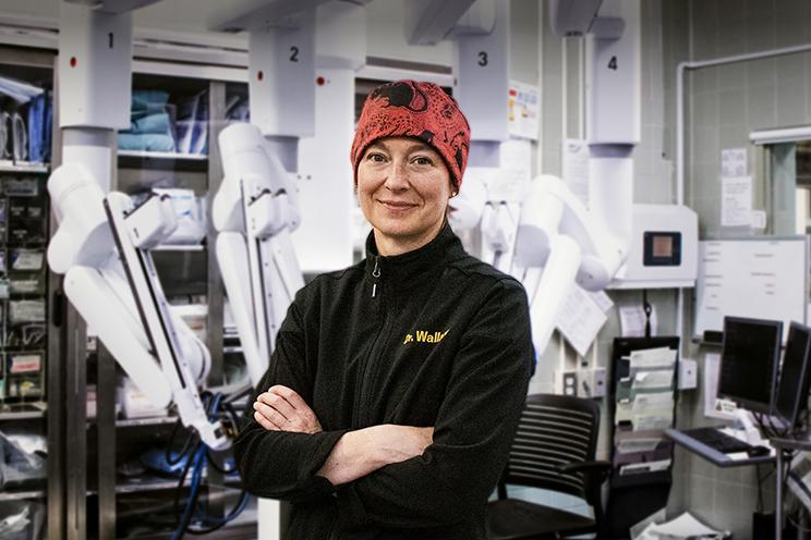 Dr. Allison Wallace poses with the daVinci Xi surgical robot in the background.