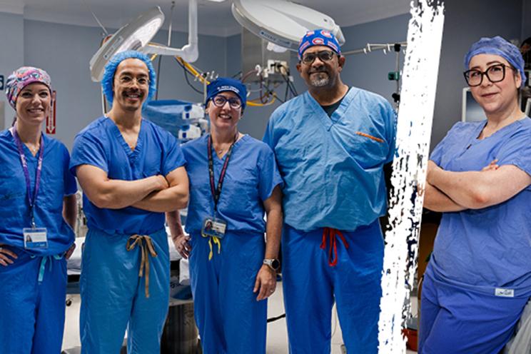 Five QEII anesthesiologists in blue scrubs pose for the camera in an operating room.