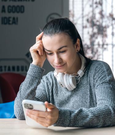 A woman using headphones and a mobile phone