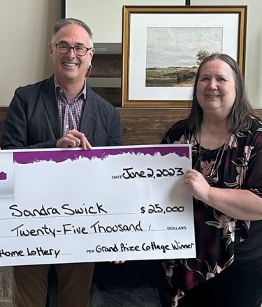 QEII Foundation leaders hand out a cheque to a female winner in Jun 2023