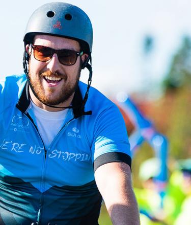 Ride for Cancer participant rides through and finish line and pumps his fist