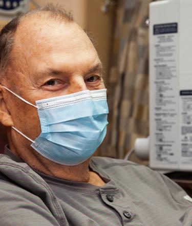 Male patient sitting in chair undergoing chemotherapy at hospital