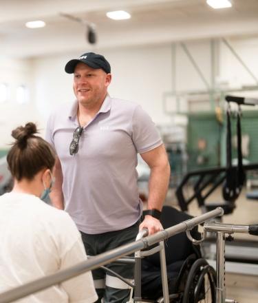A man uses hand rails to stand during physical rehabilitation therapy. 
