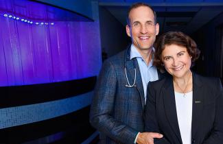 Drs. Rutlege and Ilie pictured in front of purple wall in the QEII Cancer Centre