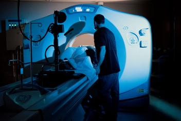 Radiation therapist comforts a patient being scanned by the QEII's CT simulator machine, which resembles a CT scanner