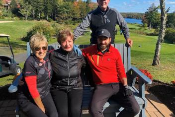 Individuals sitting on bench at a sunny golf course