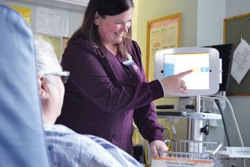 A registered nurse guides a patient through communication using the Interpreter on Wheels