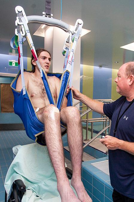 Matt Upham is being lifted into the pool by the chair lift at the The Grace Hansen Therapeutic Pool